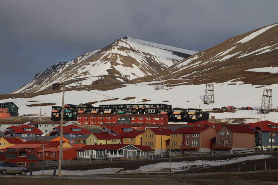Colorful houses of Longyearbyen below snow-streaked Arctic mountains.