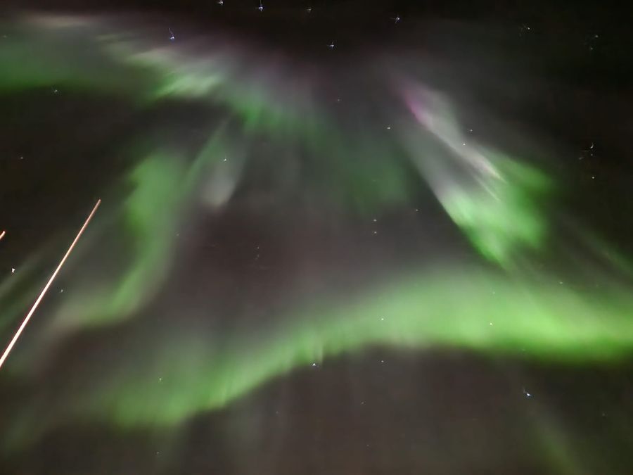 Green and faint pink aurora corona spreading overhead across the night sky.
